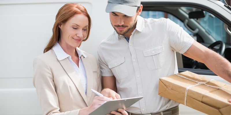 Delivery driver showing where to sign to customer outside the warehouse